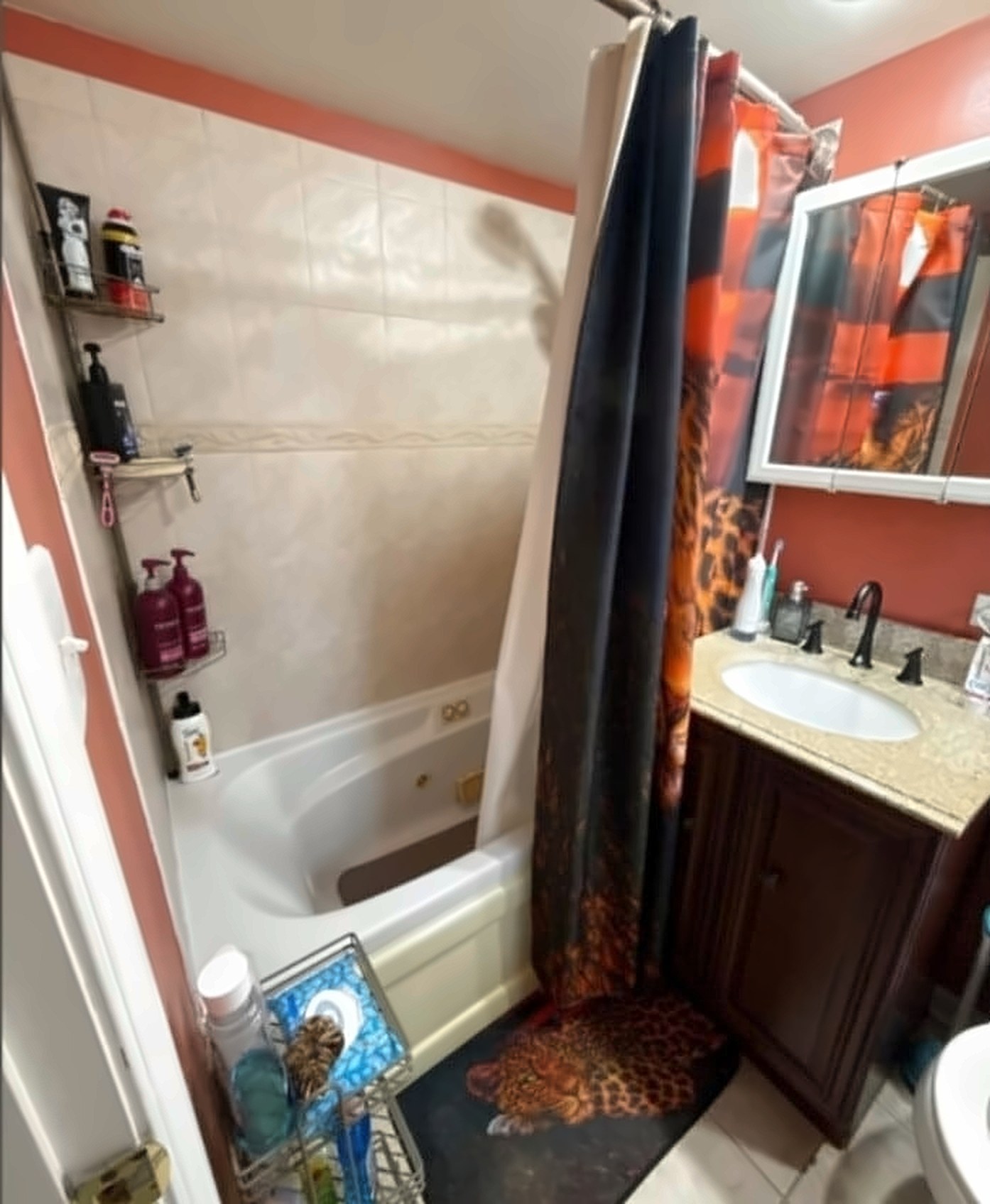 Before: an outdated bathroom with a coral accent wall and patterned shower curtain