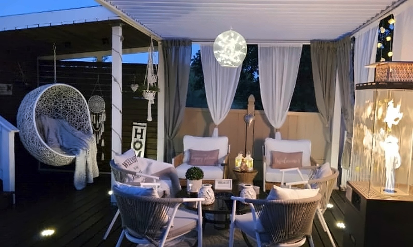 After: the same deck styled for evening with string lighting, curtains and lounge seating