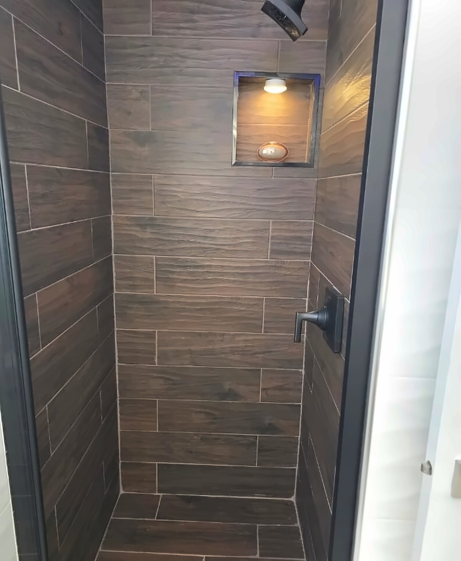 After: the same shower rebuilt with wood-look tile, a niche and a glass door
